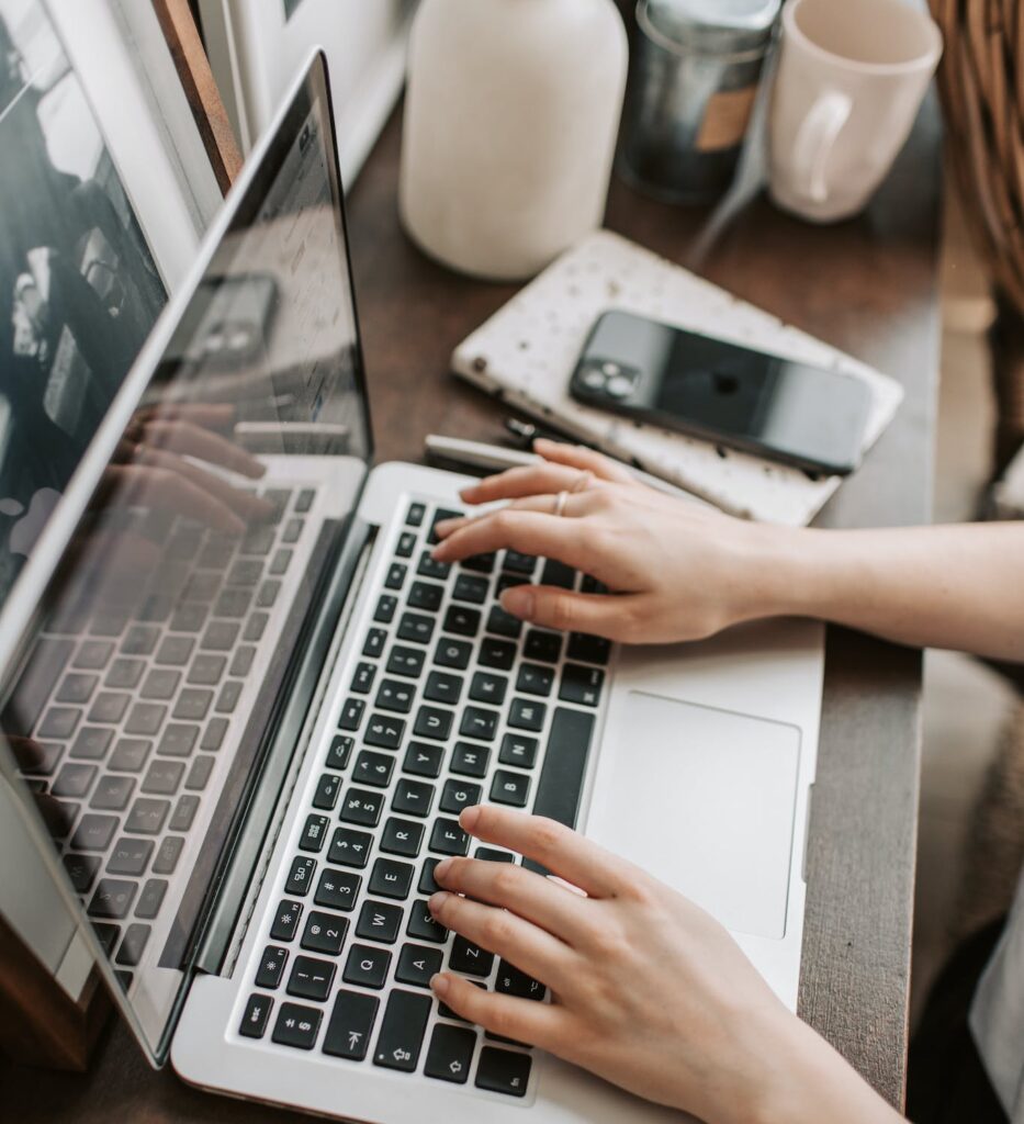 unrecognizable woman sitting at table and typing on keyboard of computer