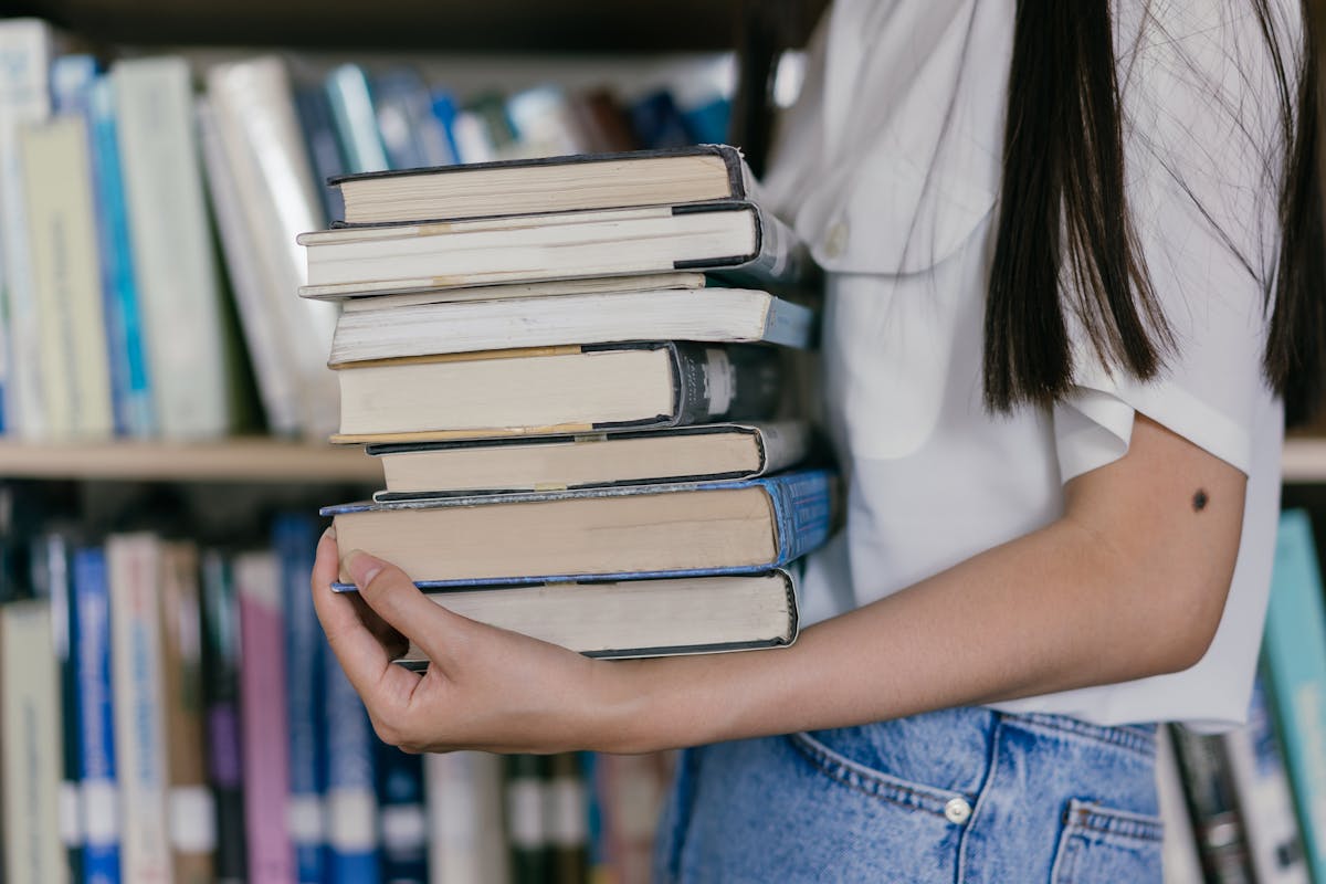 A woman's arms, carrying a heavy Stack of Books