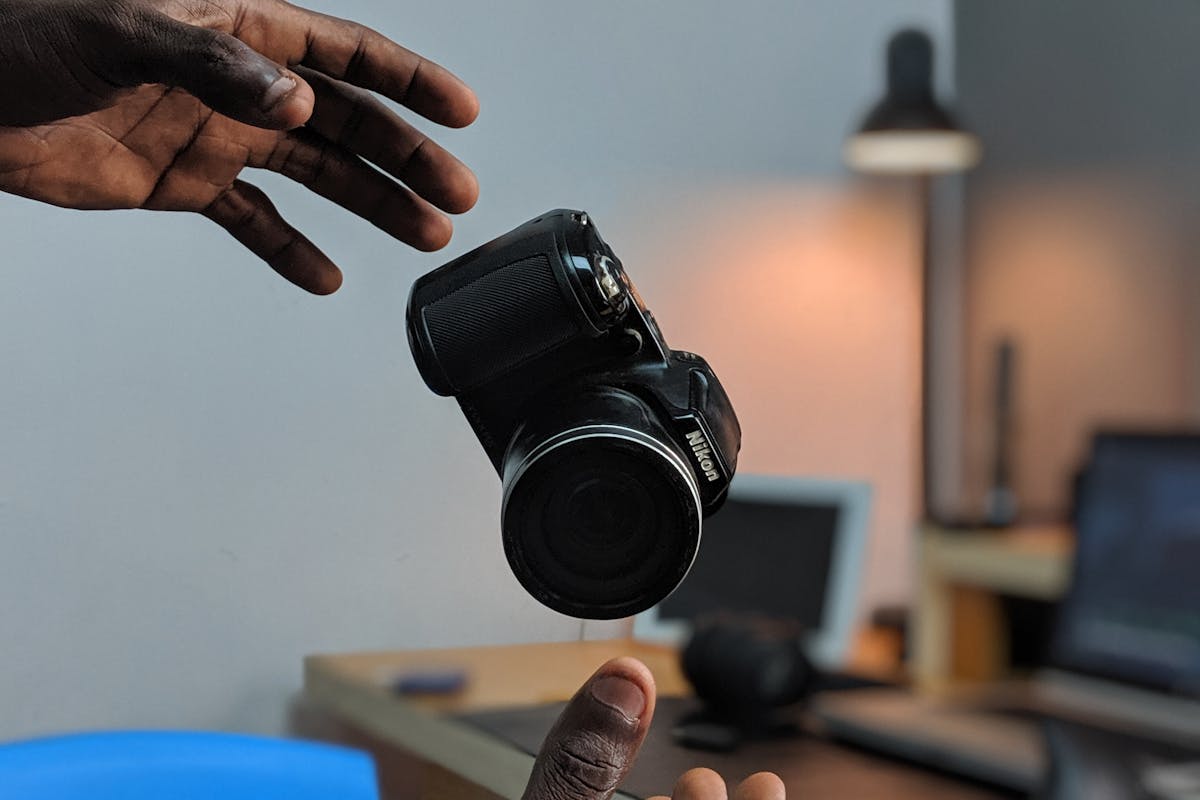 the hands of a black man lurch to catch his falling camera