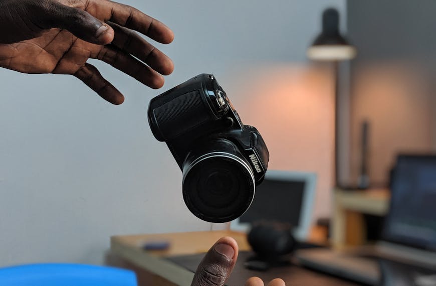 the hands of a black man lurch to catch his falling camera