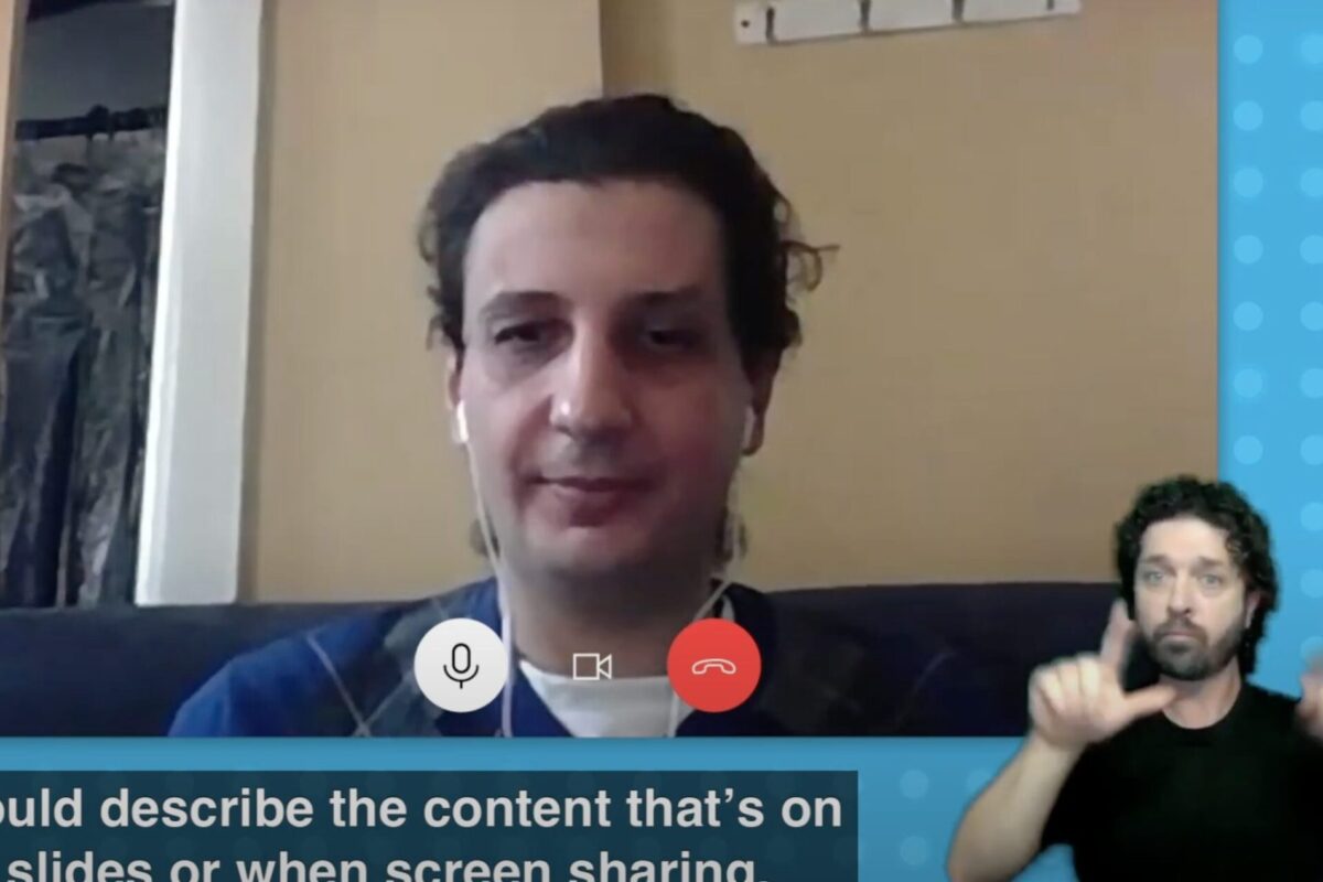 Person speaking on a video call with an ASL interpreter in the bottom corner of the screen
