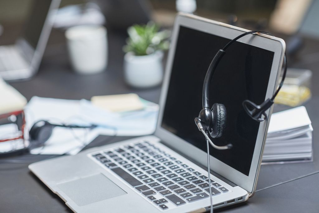 A headset placed on a laptop in a modern, cluttered desk.