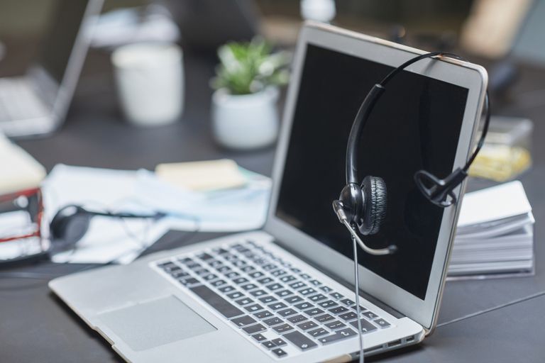 A headset placed on a laptop in a modern, cluttered desk.