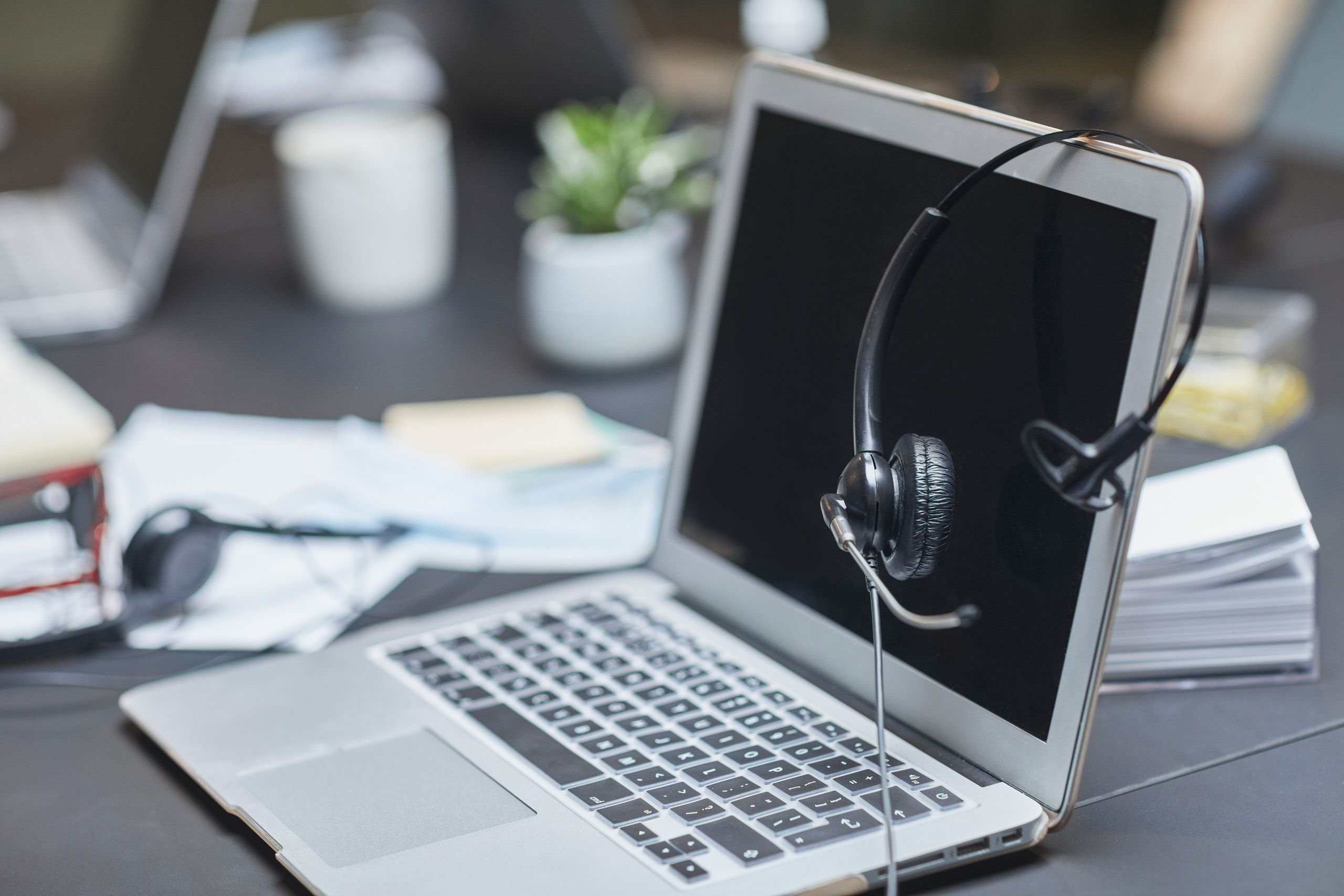 A headset placed on a laptop in a modern, cluttered desk.